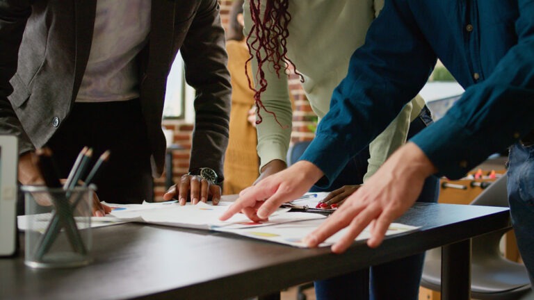 diverse-team-coworkers-looking-business-charts-documents-analyzing-research-information-statistics-diagrams-review-people-using-papers-with-infographics-data-report-close-up